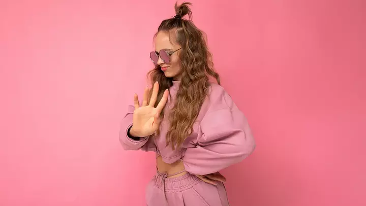 say no An attractive young woman on pink background with long hair in pink crop hoodie who has learned how to say no